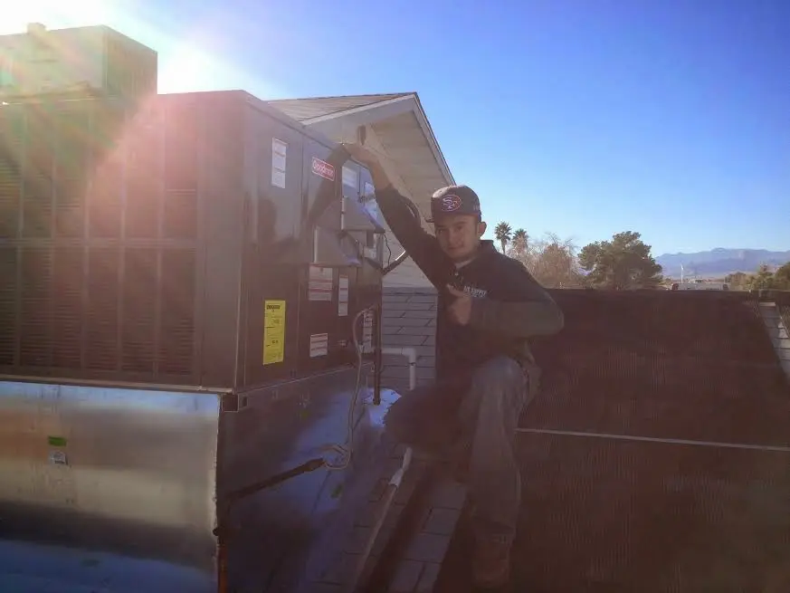 HVAC technician performing Air Duct Cleaning on a rooftop unit in Newstead